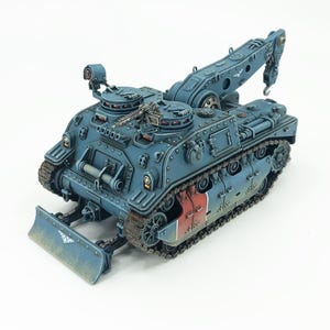 Op de afbeelding: Gedetailleerd model van een blauw en grijs rupsvoertuig met een kraanarm en een voorblad. Het model heeft een machinegeweer, klinknagels en rood-witte strepen. Het voertuig is ontworpen met een militaire esthetiek.