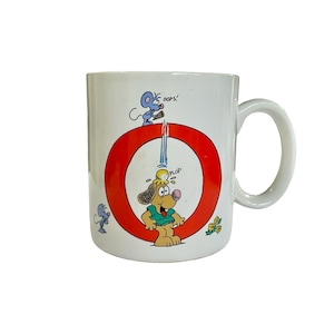 May include: A white ceramic mug featuring a large red letter O. Inside the O, a cartoon dog in a green shirt has a yellow substance dripping on its head with the text PLOP. Above, a blue mouse holds an ice cream cone with the text OOPS!