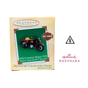 May include: A red, white, and blue Hallmark Keepsake ornament featuring a 1933 Harley-Davidson Flathead Model VLD motorcycle. The ornament is part of the Miniature Collector's Series.