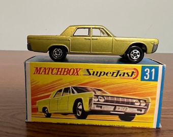 May include: A gold Matchbox Superfast 31 die-cast toy car model of a Lincoln Continental. The car is on a blue and yellow box with the Matchbox Superfast logo and the number 31.