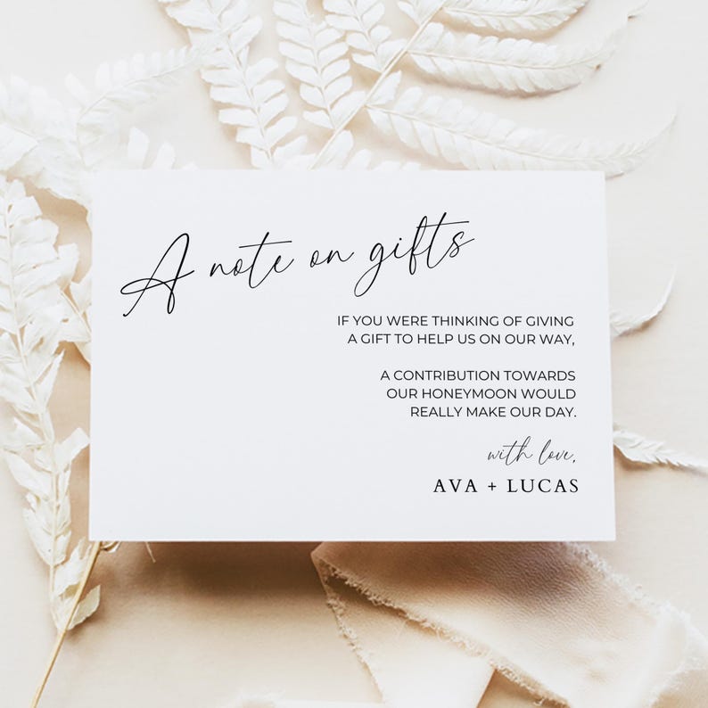 May include: A white card with black text that reads "A note on gifts" and explains that a contribution towards the couple's honeymoon would be appreciated. The card is signed "with love, AVA + LUCAS".