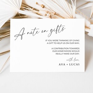 May include: A white card with black text that reads "A note on gifts". The text continues, "If you were thinking of giving a gift to help us on our way, a contribution towards our honeymoon would really make our day. With love, Ava + Lucas."
