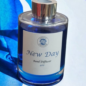 May include: A blue glass bottle with a silver lid and a white label that reads "New Day Reed Diffuser 4 oz" and a logo that says "Scent2U Creations".