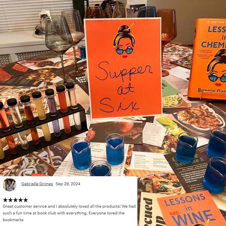 May include: A table setting with wine glasses, test tubes, and blue drinks. An orange sign reads "Supper at Six." A book titled "Lessons in Chemistry" is visible. The scene suggests a book club or tasting event.