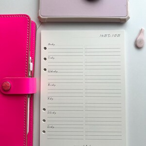 May include: A white weekly planner with a cream colored paper insert. The planner has a simple design with a black and white logo that says "Blush Rubber Co.". The dates on the planner are "1-6-25 to 1-12-25".