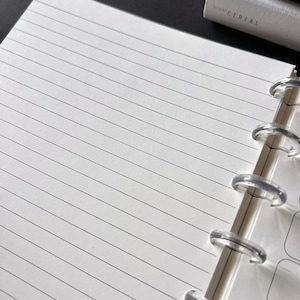 May include: A white notebook with a clear plastic binding. The notebook has lined pages and is open to a blank page.