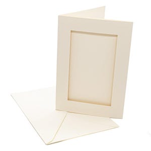 May include: A cream-colored folded greeting card with a rectangular die-cut window on the front cover, accompanied by a matching cream-colored envelope. The card features a textured paper surface and a clean, vertical orientation for display.