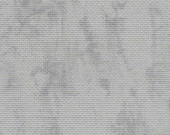 May include: A close-up of a textured, off-white fabric with subtle gray patterns. The fabric has a woven appearance, with horizontal lines creating a ribbed effect. The gray patterns appear to be slightly faded or distressed.