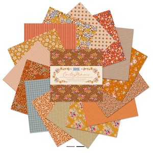 Puede incluir: Una colección de piezas de tela cuadradas dispuestas en forma de estrella. Las telas presentan varios estampados otoñales que incluyen flores, rayas, lunares y cuadrículas en tonos naranja, marrón, azul y crema. Una banda central de papel dice Creating Memories Charm Pack 5 x 5, 42 Pieces.
