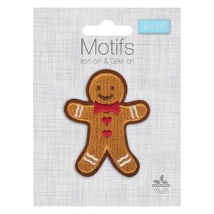 May include: A gingerbread man embroidered patch on a display card labelled Motifs Iron on & Sew on by Trimits. The patch is light brown with a dark brown border, featuring a red bow tie, two red heart buttons, and white icing details on the limbs.