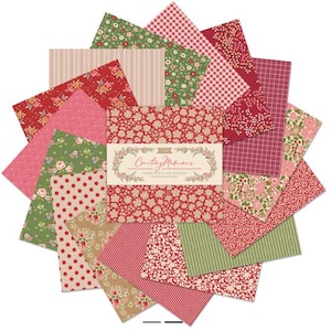 Op de afbeelding: Een charm pack van 32 stoffen vierkanten van 12,7 cm bij 12,7 cm, met diverse rode, groene en beige patronen zoals bloemenprints, stippen, strepen en vichy. De centrale band bevat de tekst Creating Memories.