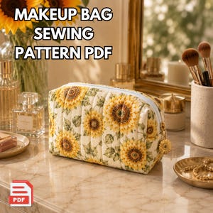 Puede incluir: Un neceser acolchado con un estampado de girasoles, cremallera azul claro y un charm de girasol dorado. El texto "MAKEUP BAG SEWING PATTERN PDF" se muestra en la parte superior. La bolsa está sobre una superficie de mármol.