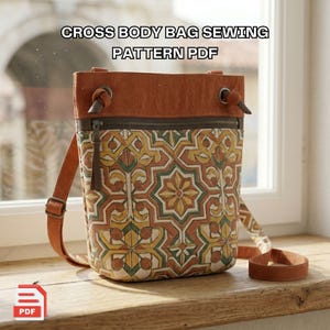 Pode incluir: Um padrão de costura PDF para uma bolsa transversal. A bolsa apresenta um padrão geométrico em tons de amarelo, verde e castanho. Possui uma alça e parte superior de couro castanho, com fecho de correr. O texto "CROSS BODY BAG SEWING PATTERN PDF" é exibido no topo.