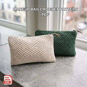 Könnte beinhalten: Zwei handgefertigte Häkel-Make-up-Taschen, eine hellbeige und die andere dunkelgrün. Beide haben ein strukturiertes, gewebtes Aussehen und einen Reißverschluss. Der Text "MAKEUP BAG CROCHET PATTERN PDF" steht oben.