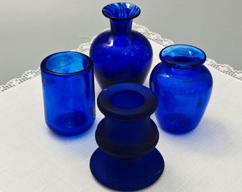 Tres jarrones pequeños y un portavelas de color azul cobalto.