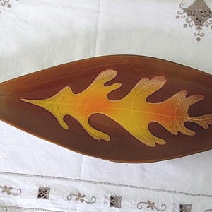 May include: A ceramic serving dish shaped like a leaf with a brown, orange and yellow glaze.