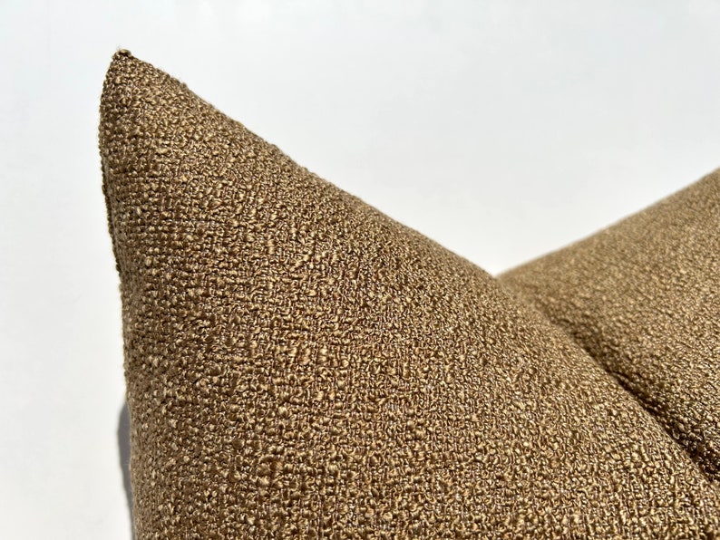 May include: Close-up of a brown textured pillow with a subtle sheen. The fabric has a woven, almost tweed-like appearance.