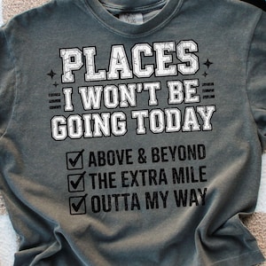 Può includere: T-shirt grigio con la scritta bianca "PLACES I WON'T BE GOING TODAY". Sotto, tre caselle di controllo con le frasi "ABOVE & BEYOND", "THE EXTRA MILE" e "OUTTA MY WAY".