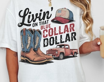 Puede incluir: Camiseta blanca con un diseño gráfico que presenta un par de botas de vaquero, una camioneta pickup y una gorra de béisbol con una bandera estadounidense. El texto en la camiseta dice "Livin' on that Blue Collar Dollar."