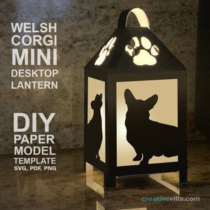 May include: A black paper lantern with a silhouette of a Welsh Corgi and paw prints. The lantern is lit from inside, casting a warm glow. The text "WELSH CORGI MINI DESKTOP LANTERN DIY PAPER MODEL TEMPLATE SVG, PDF, PNG" is printed on the image.