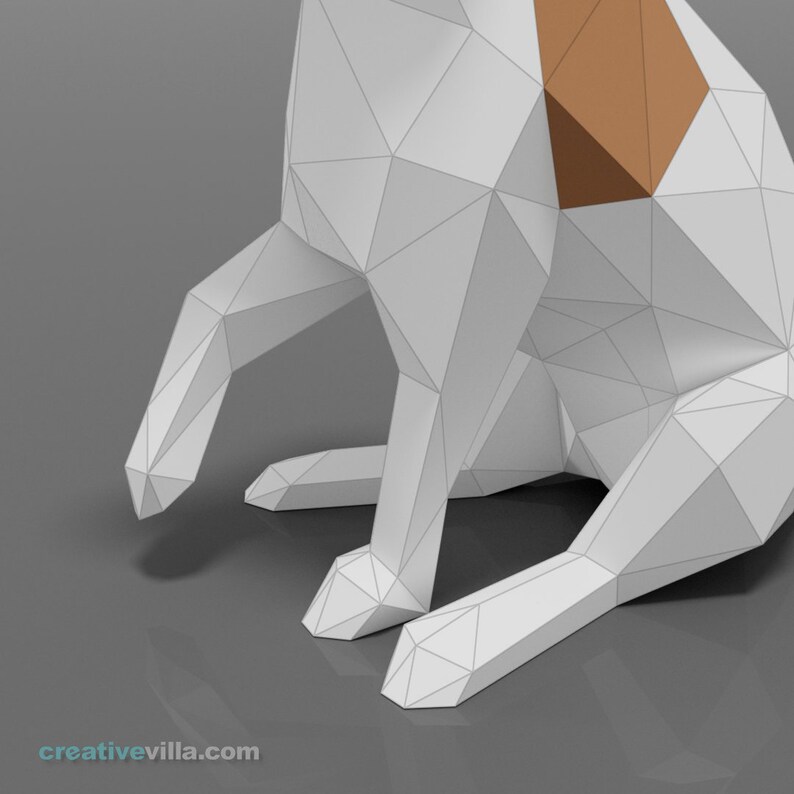 Pu&ograve; includere: Un cane di origami bianco con macchie marroni &egrave; seduto su una superficie grigia. Il cane &egrave; fatto di carta e ha un design geometrico.