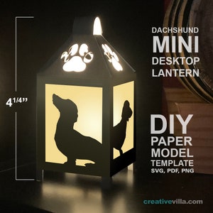 May include: A black dachshund mini desktop lantern, 4 1/4 inches tall, with paw print cutouts and dachshund silhouettes. The lantern is a DIY paper model template. Text on the image reads "DACHSHUND MINI DESKTOP LANTERN DIY PAPER MODEL TEMPLATE SVG, PDF, PNG".