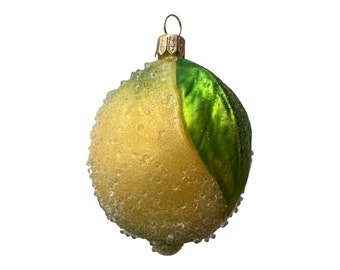 Op de afbeelding: Een kerstversiering in de vorm van een citroen. De gele ornament heeft een getextureerd, met kralen bezet oppervlak en een groen blad. Het heeft een goudkleurige metalen dop en een lus om op te hangen.