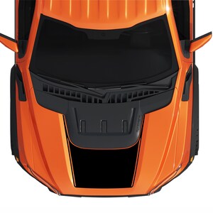Pode incluir: Vista superior de uma caminhonete laranja com uma entrada de ar preta no capô e listras de corrida pretas. A caminhonete tem espelhos laterais pretos e para-lamas pretos.