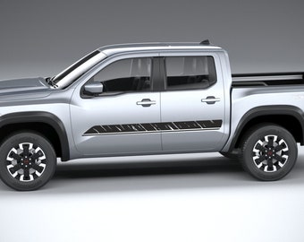 May include: A silver pickup truck with black accents, including the wheel wells and side panel decals. The truck has black and silver wheels and a black bed. The image is a studio shot.