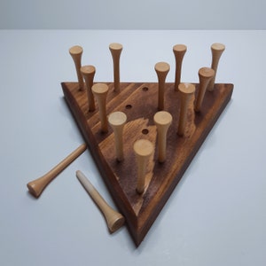 May include: A wooden triangular game board with 15 wooden pegs arranged in a pattern. Two pegs are lying off the board.
