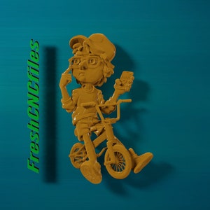 May include: A yellow 3D printed figurine of a person wearing glasses and a hat, riding a bicycle. The figurine is on a blue background with the text "FreshCNCfiles" in green.