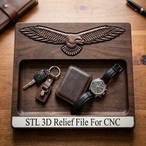 May include: A dark brown wooden valet tray featuring a carved eagle with spread wings on the top edge. The tray contains a set of keys on a brown leather fob, a brown leather wallet, and a black wristwatch. A white label reads STL 3D Relief File For CNC.