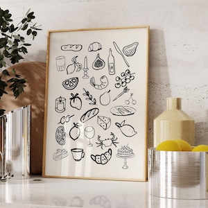 May include: A black and white illustration of various food and drink items, including a baguette, grapes, a glass of wine, a lemon, a crab, and a fig. The illustration is framed in a light wood frame and is hanging on a wall.