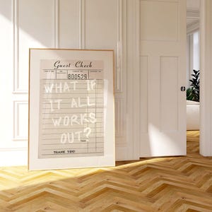 Puede incluir: Una impresi&oacute;n enmarcada con un dise&ntilde;o vintage de "Guest Check", que muestra el texto "WHAT IF IT ALL WORKS OUT?". La obra de arte est&aacute; en una habitaci&oacute;n con paredes blancas, suelo de madera y una puerta abierta.