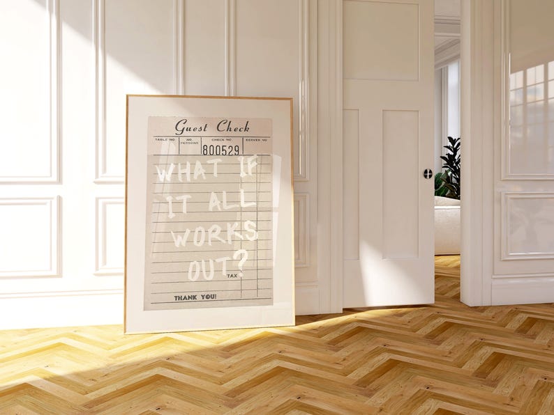 Puede incluir: Una impresi&oacute;n enmarcada con un dise&ntilde;o vintage de "Guest Check", que muestra el texto "WHAT IF IT ALL WORKS OUT?". La obra de arte est&aacute; en una habitaci&oacute;n con paredes blancas, suelo de madera y una puerta abierta.