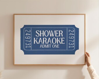 May include: A framed print featuring a blue ticket design with the words "Shower Karaoke" and "Admit One" in white. The ticket has the number "249731" printed on each side. The frame is made of light brown wood.
