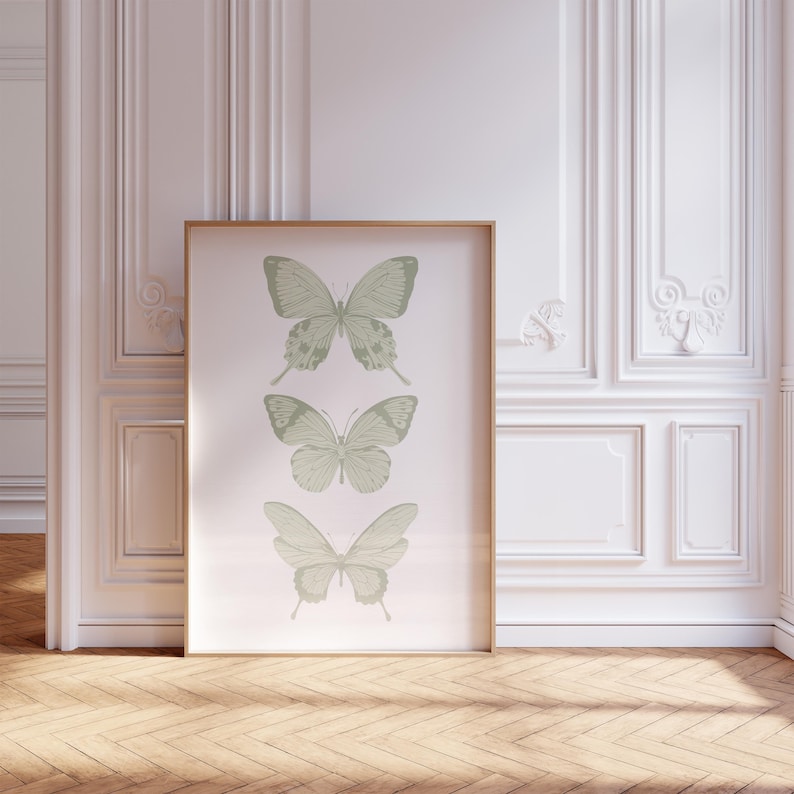 May include: A framed print featuring three green butterflies on a white background. The butterflies are arranged vertically, with the largest butterfly at the top and the smallest butterfly at the bottom.