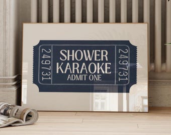 May include: A framed print featuring a navy blue ticket design with the words "Shower Karaoke" and "Admit One" in white. The ticket has a vintage aesthetic, with the number "249731" printed on each side.