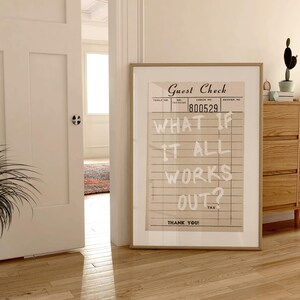 Puede incluir: Un estampado enmarcado con un dise&ntilde;o vintage de "Guest Check" con el texto "WHAT IF IT ALL WORKS OUT?". La obra de arte se exhibe en una habitaci&oacute;n con pisos de madera y una c&oacute;moda de madera.