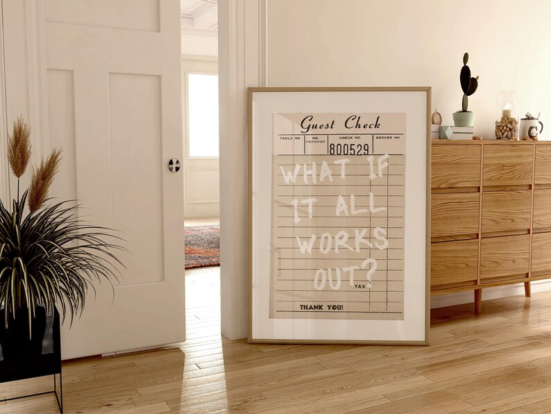 Puede incluir: Un estampado enmarcado con un dise&ntilde;o vintage de "Guest Check" con el texto "WHAT IF IT ALL WORKS OUT?". La obra de arte se exhibe en una habitaci&oacute;n con pisos de madera y una c&oacute;moda de madera.