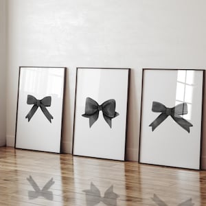 Puede incluir: Tres impresiones enmarcadas en blanco y negro de ilustraciones de lazos en acuarela. Cada impresión presenta un solo lazo en un estilo diferente.