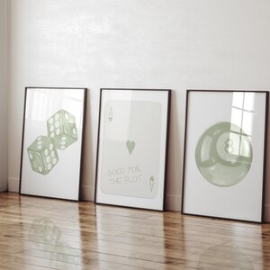 May include: Three framed prints with a white background. The left print features a pair of green dice. The middle print features a green ace of spades with the text "Good for the plot". The right print features a green 8-ball.