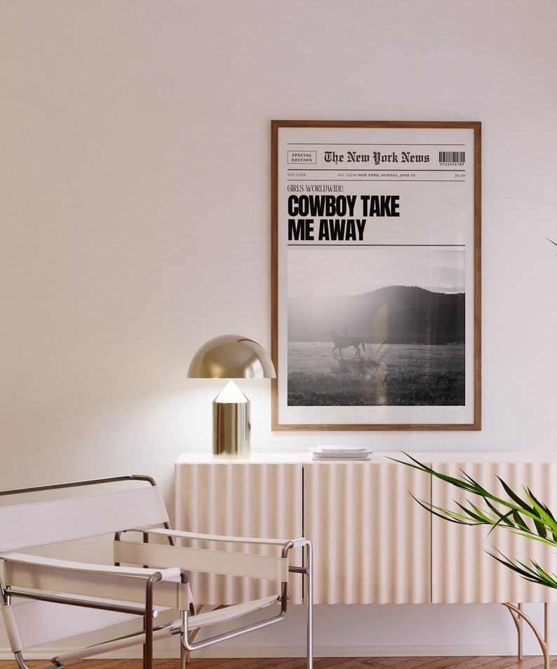 May include: A framed black and white newspaper print with the headline "COWBOY TAKE ME AWAY" and a photo of a horse and rider in a field. The newspaper is titled "The New York News" and has a special edition label.