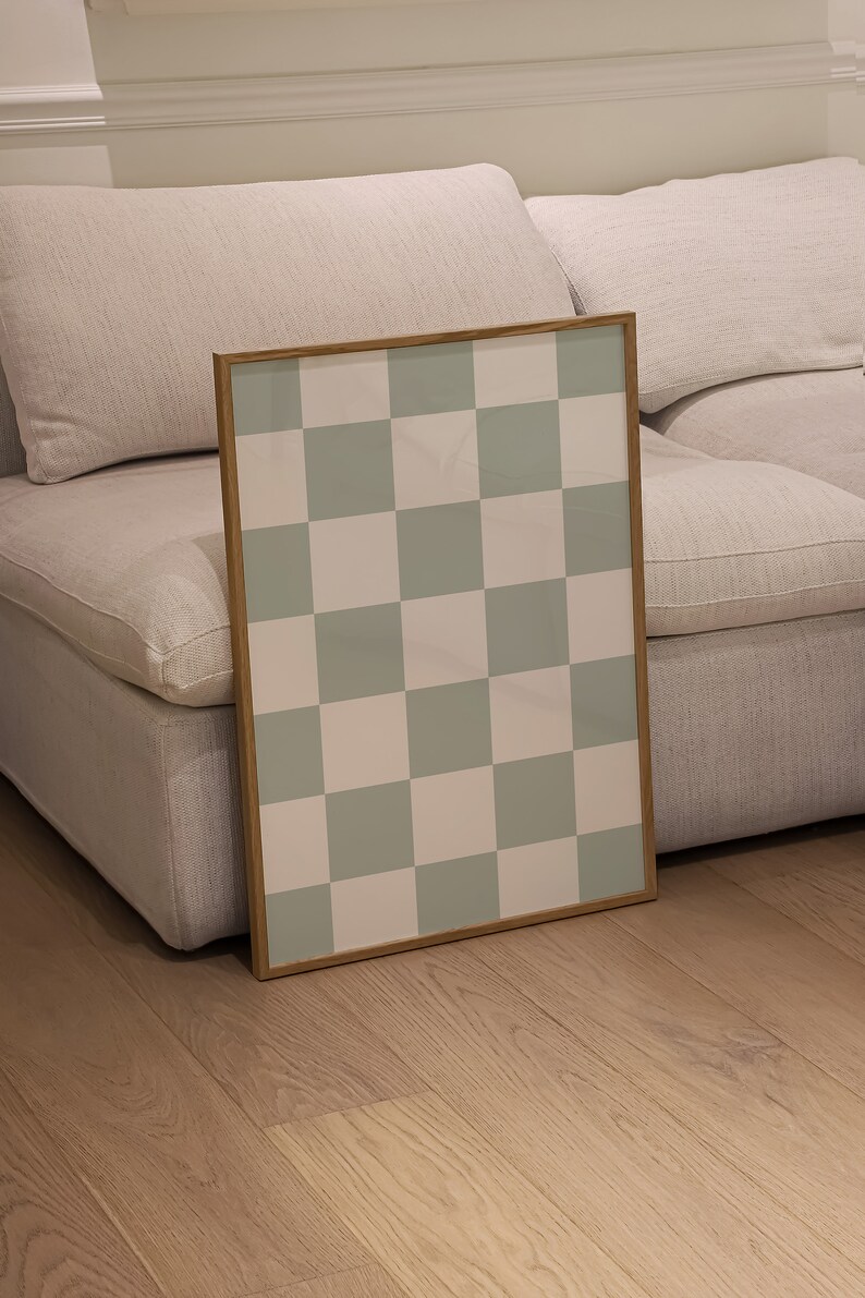 Puede incluir: Una impresi&oacute;n enmarcada con un patr&oacute;n a cuadros en tonos de verde y blanco. La impresi&oacute;n se apoya en un sof&aacute; blanco.