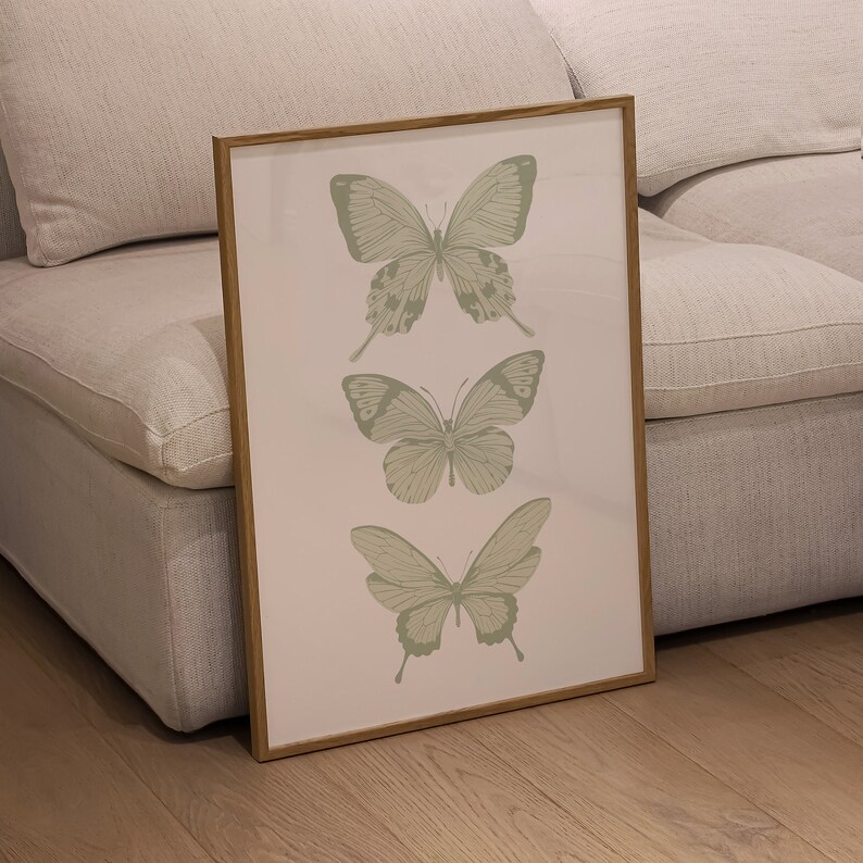 May include: A framed print featuring three green butterflies on a white background. The butterflies are arranged vertically, with the largest butterfly at the top and the smallest butterfly at the bottom.