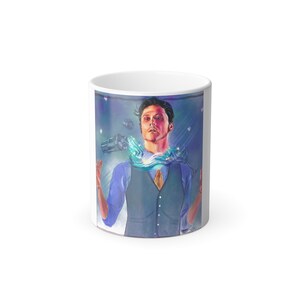 May include: White ceramic mug featuring a colorful illustration of a person in a vest and shirt, with a cocktail shaker and flowing blue liquid. The artwork has a fantasy theme with a purple and blue background.
