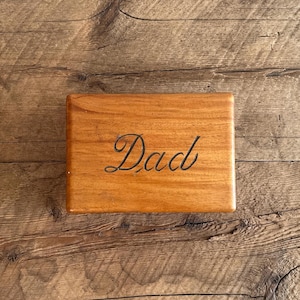 以下が含まれることがあります： 上に「Dad」と刻まれた木製の箱