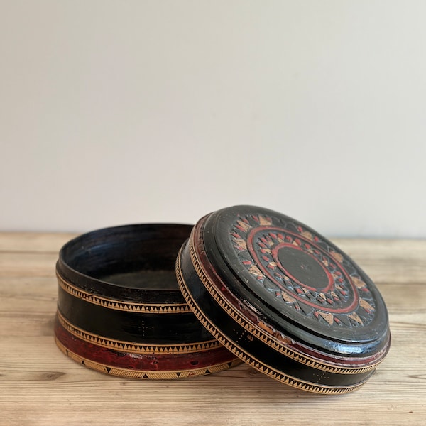 Antique round Burmese betel lacquer box, with black, gold and red geometric designs