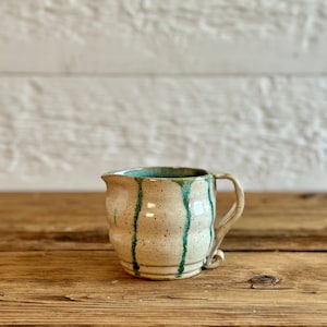 Vintage hand-made ceramic milk pitcher or creamer, with beige and green glaze, signed Murial