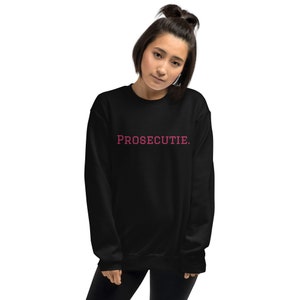 May include: Black sweatshirt with the text "PROSECUTIE." in pink lettering.